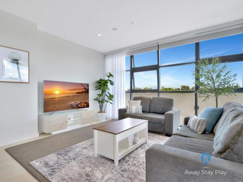 Una sala de estar con un sofá y un televisor. en CODA 410, en Coffs Harbour