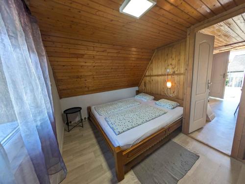 a small bedroom with a bed in a wooden room at Holiday home in Zamardi - Balaton 53551 in Zamárdi
