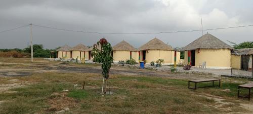 a row of houses with a tree in a field at Rann Roshni homestay in Bherandiāla