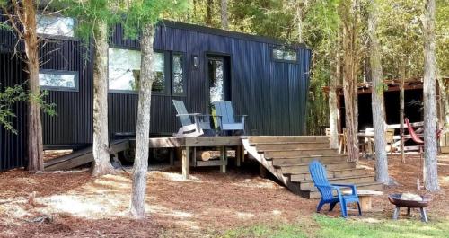 een blauw huis met twee stoelen en een houten terras bij Stylish Tiny House for Glamping in South Carolina in Rock Hill