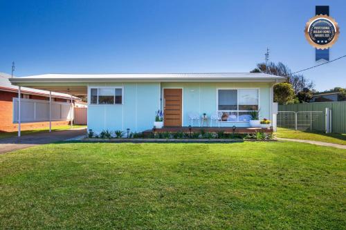 a blue house with a lawn in front of it at Periwinkle I Pet Friendly I 2 Mins Walk to Beach in Culburra Beach