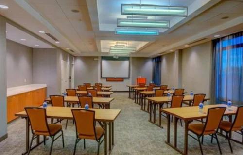 a conference room with tables and chairs and a screen at Springhill suites by Marriott in Macon