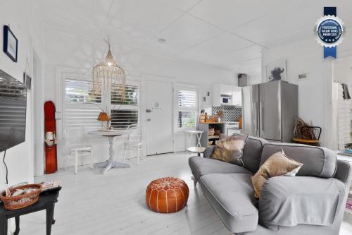 a living room with a gray couch and a kitchen at Adrift - Pet-friendly - 5 min Walk to Bay - Rustic Charm in Erowal Bay