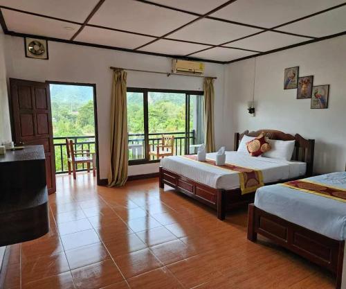 een slaapkamer met twee bedden en een balkon bij west water hostel in Vang Vieng