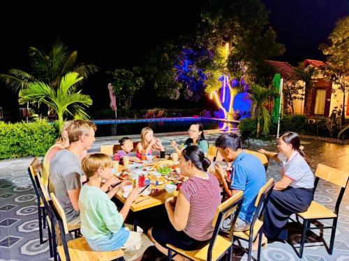 eine Gruppe von Menschen sitzt um einen Tisch herum und isst zu Abend in der Unterkunft Tam Coc Minh Quân Bungalow & Homestay in Ninh Bình