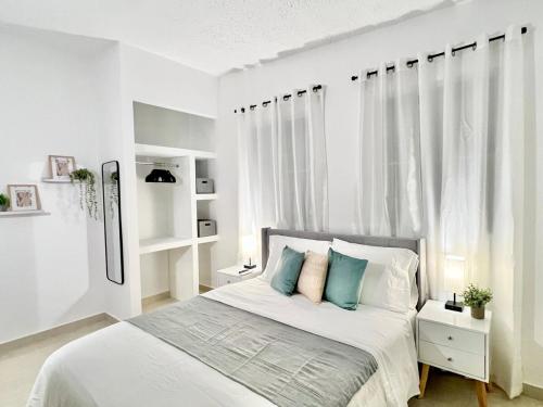 a white bedroom with a bed with blue pillows at Rich Villa Guesthouse in Bayamon