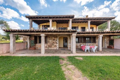 Una casa grande con una mesa delante de ella. en House and Apts. Siniscola - Sardinien 35758, en Santa Lucia