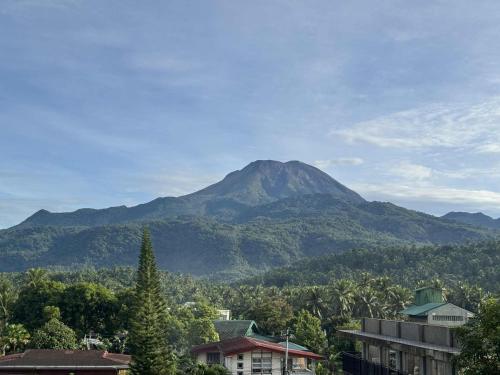 einen Berg in der Ferne mit Bäumen und Gebäuden in der Unterkunft Peaks&Pedals Transient in Irosin