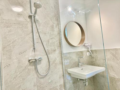 een douche met wastafel en spiegel in een badkamer bij Modern Apartment with Terrace Patio in Wiener Neudorf