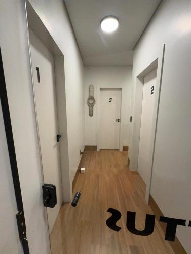 an empty hallway with two white doors and wooden floors at 1Studio ao lado da Praça Augusto Silva, PRÓXIMO À UFLA E UNILAVRAS in Lavras