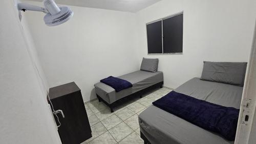 een kleine kamer met twee bedden en een raam bij Casa com Quarto e Garagem, Alto da Cruz, Camaçari in Camaçari