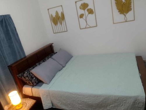 Ein Schlafzimmer mit einem Bett, einer Lampe und Bildern an der Wand in der Unterkunft Gee Staycation in Santo Tomas