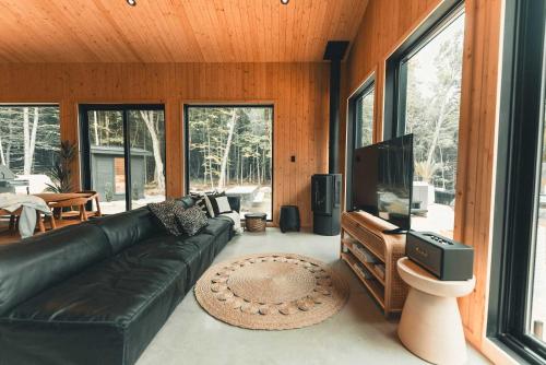 a living room with a black leather couch and a flat screen tv at Zen House 6 - Villas & Spa in Morin Heights