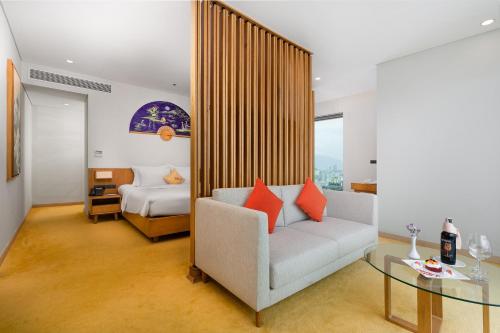 a room with a couch and a bed and a glass table at Sala Danang Beach Hotel in Danang
