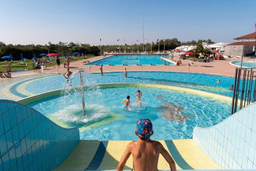 a young boy sitting in a swimming pool at Houses and Apts. in Albarella 24882 in Palazzo Vianello