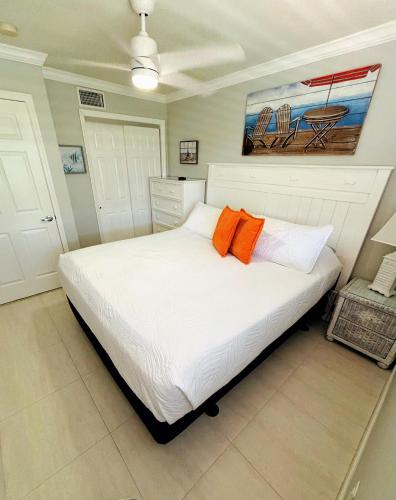 a bedroom with a white bed with two orange pillows at Welcoming 2-bedroom condo with bonus room! in Indian Shores