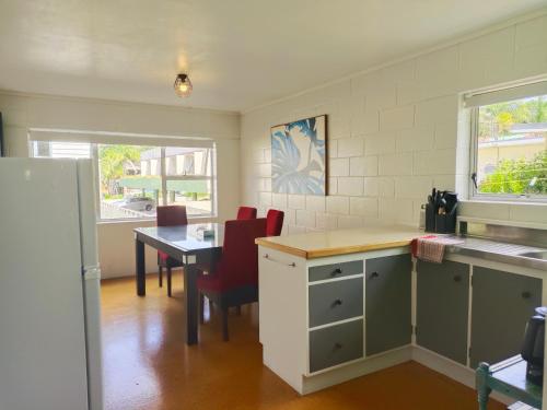 a kitchen and dining room with a table and chairs at Peppertree Lodge in Paihia