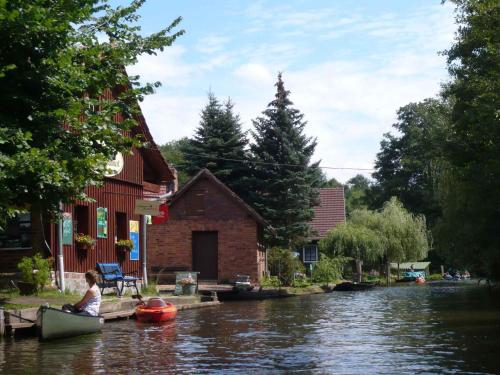 a woman sitting in a boat on a river next to a house at Apartments in Vetschau Spreewald 2618 in Vetschau
