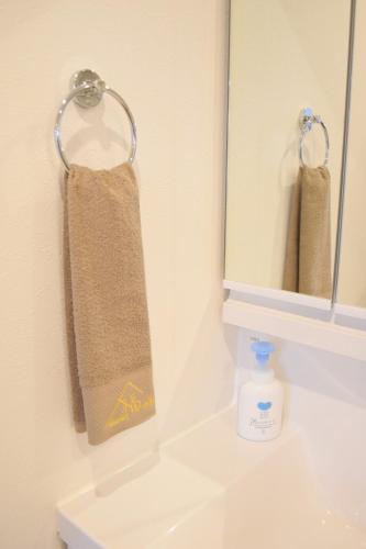 a bathroom sink with a towel hanging from a mirror at 福の荘唐人町a棟 in Fukuoka