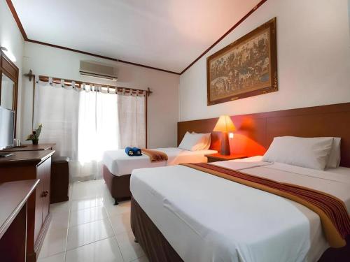 a hotel room with two beds and a television at Maha Jaya Hotel Bali in Denpasar