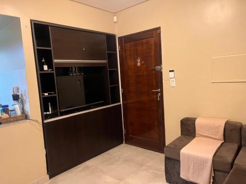 a room with a door and a chair and a television at Genetrix con Increíble pileta in San Miguel de Tucumán