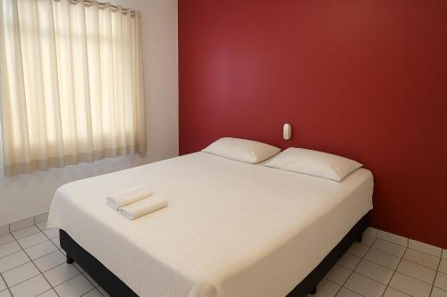 a bedroom with a large white bed with red walls at Amarante Hotel in Juazeiro