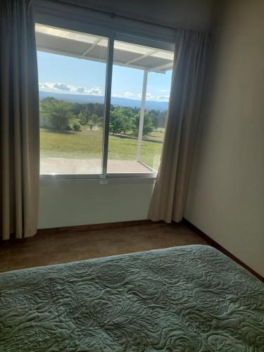 a bedroom with a large window looking out at a field at Bosquemolinos in Villa Los Molinos