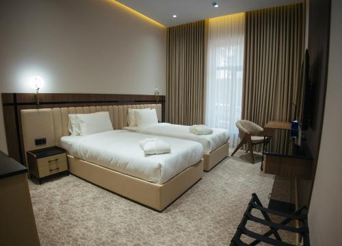 サマルカンドにあるAD Bellagioの大きなベッドと机があるホテルの部屋