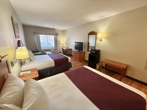 a hotel room with two beds and a television at Americas Best Value Inn Wiggins in Wiggins