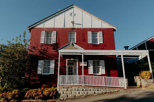 une maison rouge avec une véranda blanche dans une rue dans l'établissement Mountain Heritage Hotel, à Katoomba
