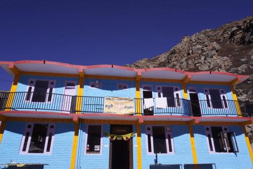 a blue and yellow building with a mountain in the background at Madhurvi baker's and homestay in Chitkul