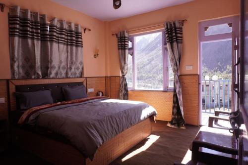 a bedroom with a bed and two windows at Madhurvi baker's and homestay in Chitkul