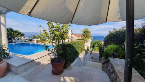 eine Terrasse mit Sonnenschirm und Swimmingpool in der Unterkunft Apartments in Lovran 15143 in Lovran