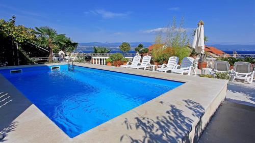 ein Schwimmbecken mit Stühlen und einem Sonnenschirm in der Unterkunft Apartments in Lovran 15143 in Lovran