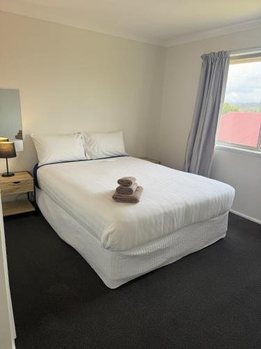 a bedroom with a white bed with a hat on it at Walcha Villas in Walcha