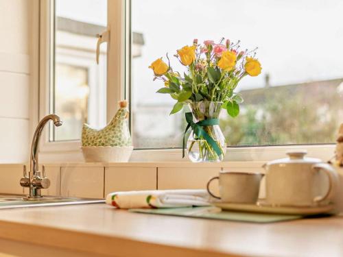 eine Küchentheke mit einer Vase aus Blumen und einem Fenster in der Unterkunft 3 Bed in Keswick 95858 in Keswick