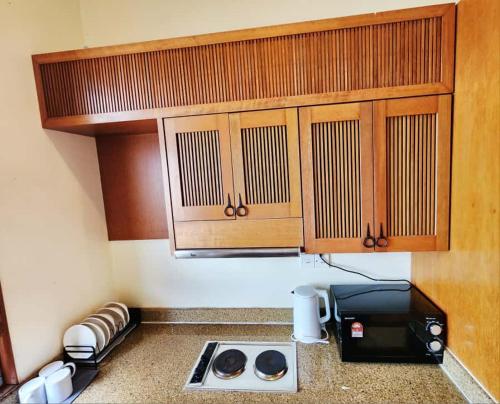a kitchen with a stove and wooden cabinets and a microwave at Sea Villa Langkawi in Kampung Padang Masirat