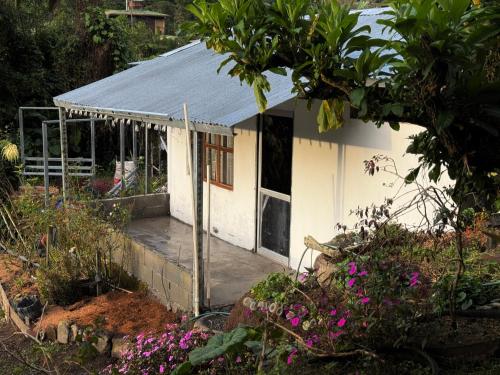 a small white building with a porch in a garden at Eco Amigo el Rincón in Cerro Punta