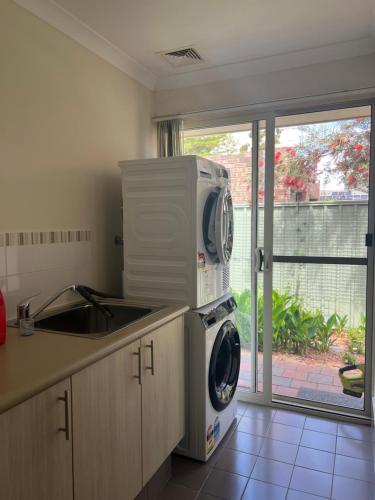 a kitchen with a microwave on top of a washing machine at Sweet Home Property in Perth