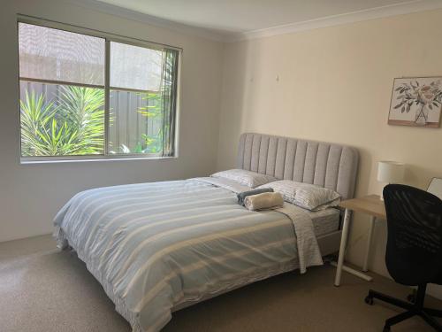 a bedroom with a bed and a desk and a window at Sweet Home Property in Perth