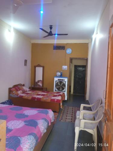 a bedroom with two beds and a ceiling fan at Bhavya Homstayes in Ujjain