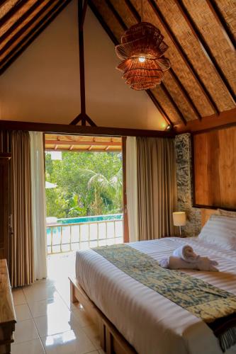 a bedroom with a bed and a large window at Mina Baturiti Hotel & Resto in Patjung