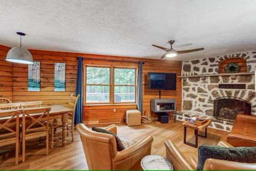 a dining room and living room with a stone fireplace at Cozy Log Cabin Near Ski Area and Lake including Hot Tub in Swanton