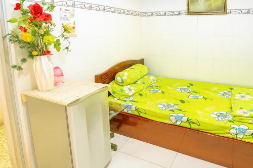a small room with a bed and a vase with flowers at Thanh Bình Hostel in Can Tho