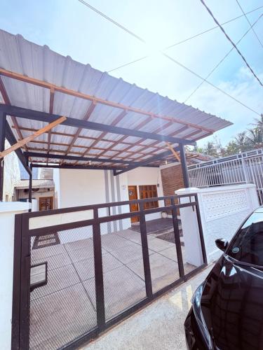 a pergola on a house with a car parked under it at Fortune Homestay Banyuwangi in Banyuwangi