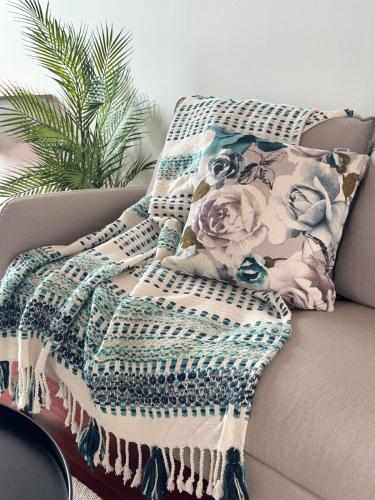 a blanket on a couch with a pillow on it at Belleview Cottage- Cute cottage with views of sea, city and snowpeeks in Christchurch