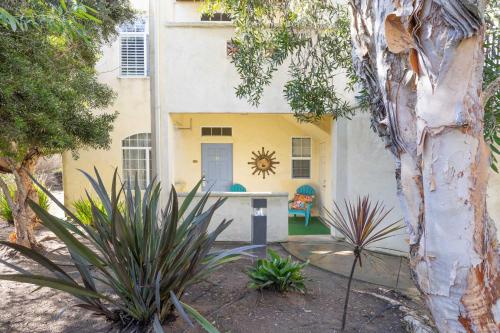 a yellow house with a blue door in a yard at Tide & Treasures in Oceano