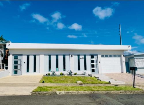 a white building with a blue sky in the background at Rich Villa Guesthouse in Bayamon