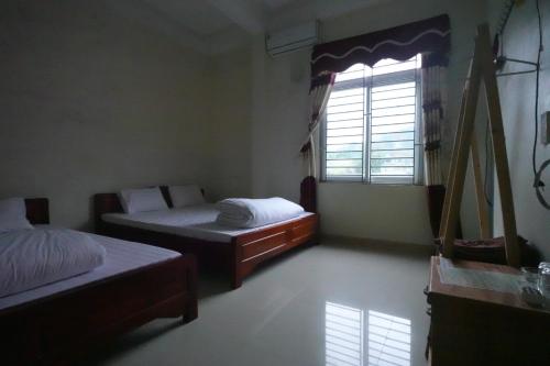 a bedroom with two beds and a window at Nhà nghỉ Ngọc Ánh in Dồng Văn