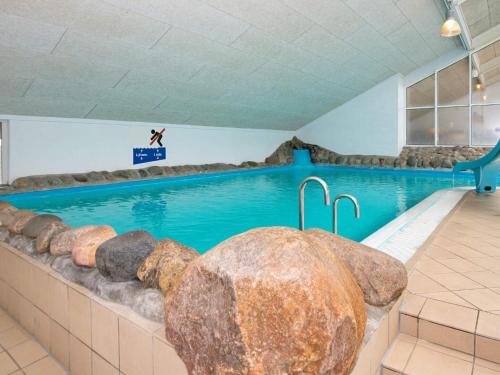 a large swimming pool with a person jumping into it at 4 person holiday home on a holiday park in Hemmet in Hemmet
